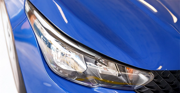 A picture of a blue car with newly restored headlights.