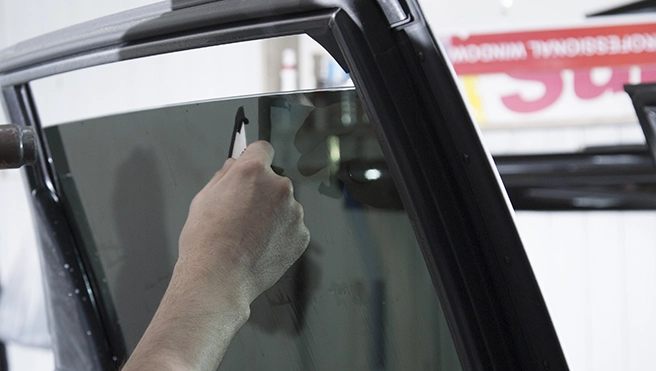 A closeup of a hand installing car window tinting.