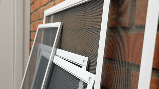 A picture of different sized window screens awaiting installation.