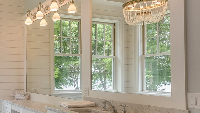 A picture of a custom glass mirror hung over a bathroom vanity.