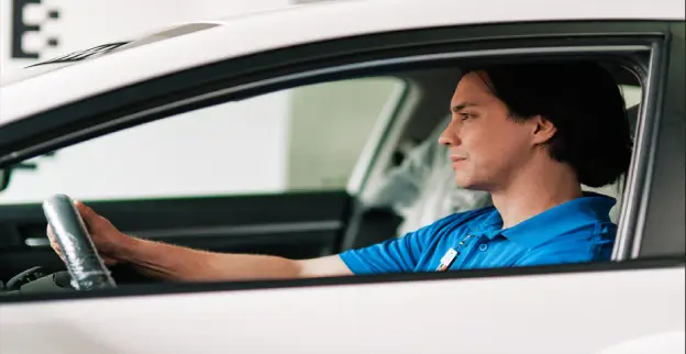 A male Glass Doctor service professional sitting in a white car on the driver’s side with the window rolled down