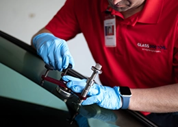 Glass Doctor professional repairing car windshield with a tool.