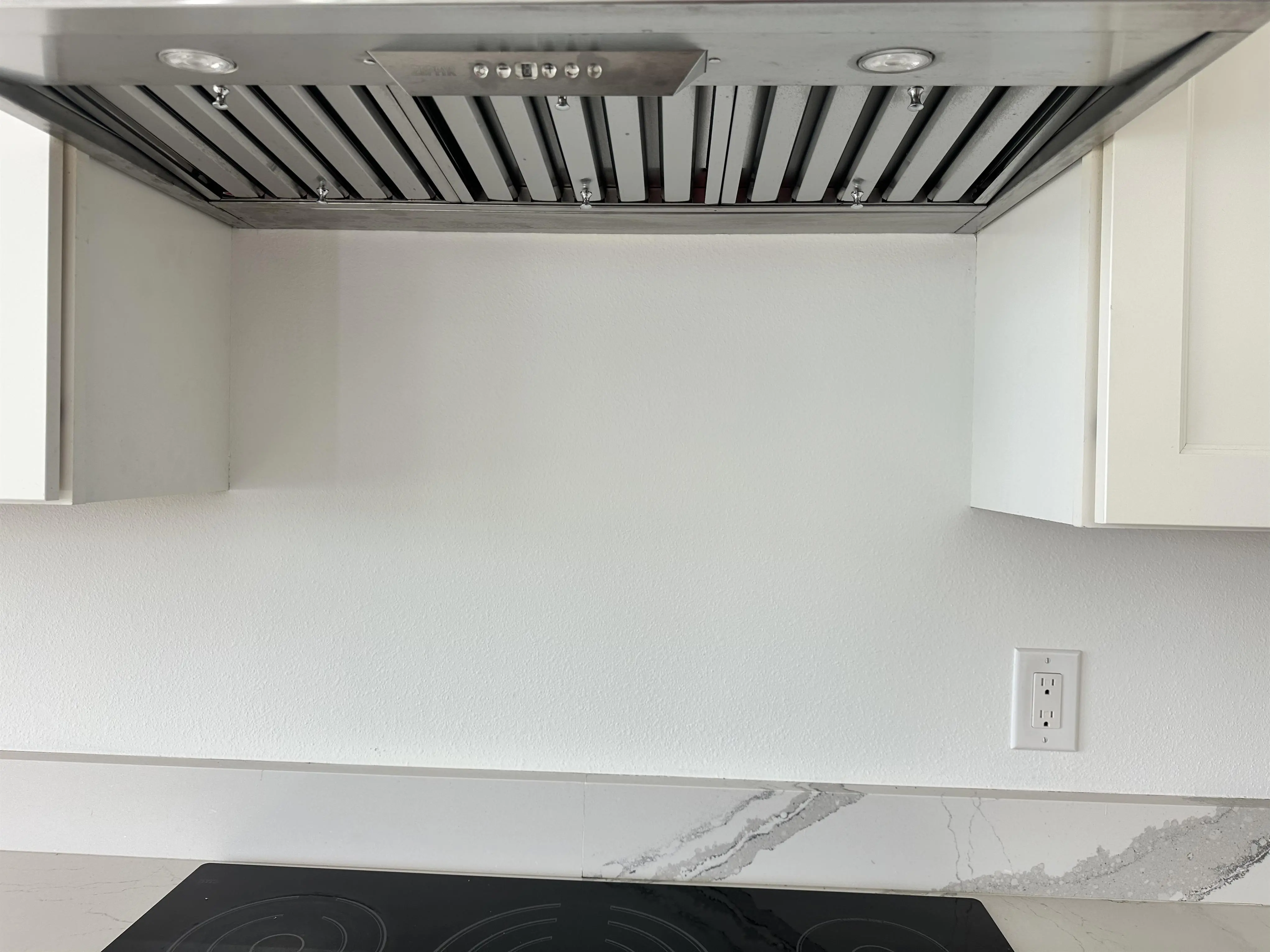 Plain white back of stove wall.