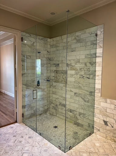 90-degree frameless glass shower enclosure with marble tile.