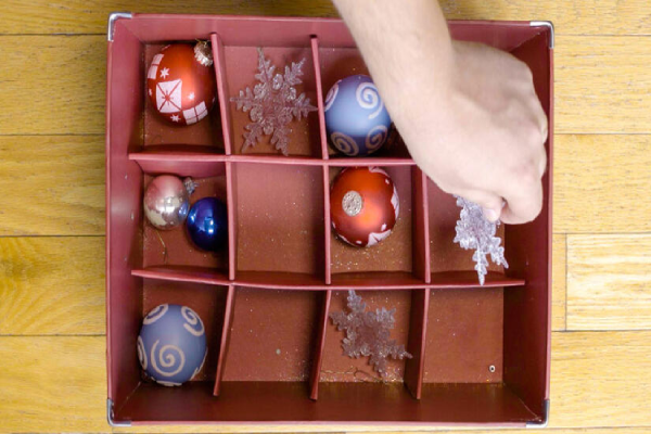 A person sorting and putting decorative ornaments into a storage box.