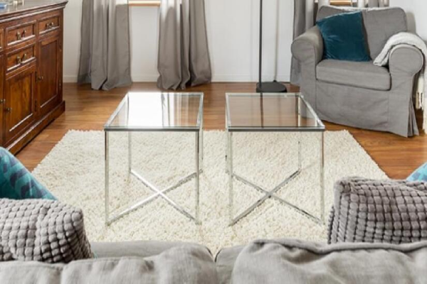 Two side tables in the middle of a living room with glass tabletops.