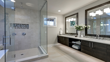 Spacious bathroom in gray tones with heated floors, walk-in shower, double sink vanity and skylights
