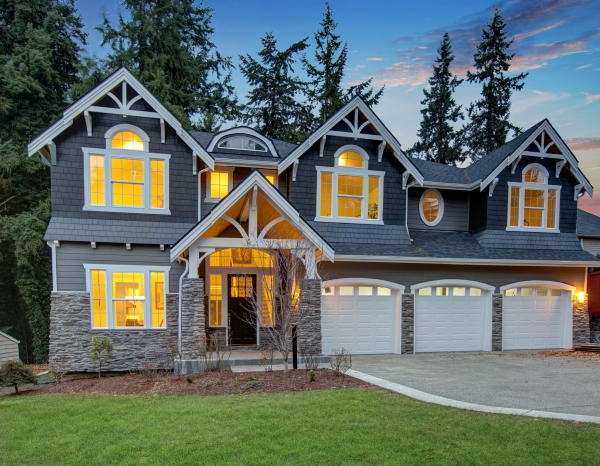Luxurious home exterior at twilight, with grey vinyl siding, white trim, and three attached garage spaces.